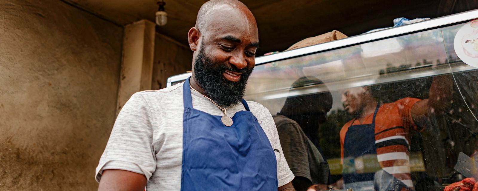 A business owner in an apron checking his phone in his shop